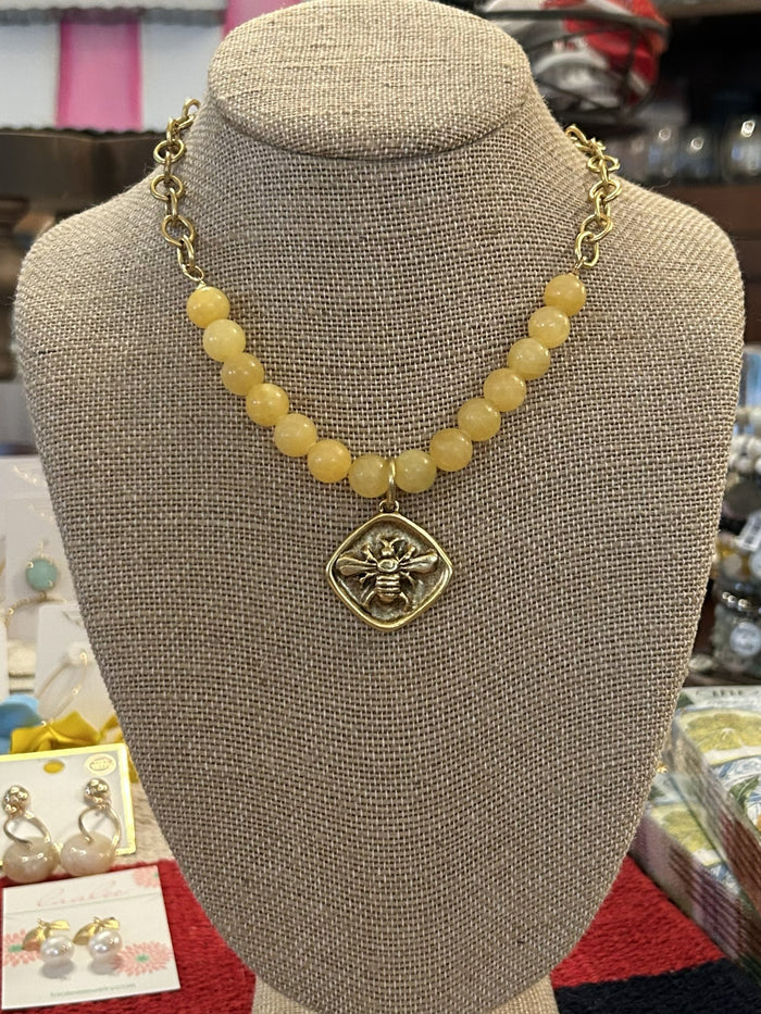 Find out what all the buzz is about! This beautiful gold chain necklace is anchored by lovely yellow beads and a bee pendant. The bee pendant has a hammered look and is diamond shaped. This is a perfect gift for the garden enthusiast, bee lover or Tech fan.
Designed and made by local artist
Approximate Length: 17-19"
