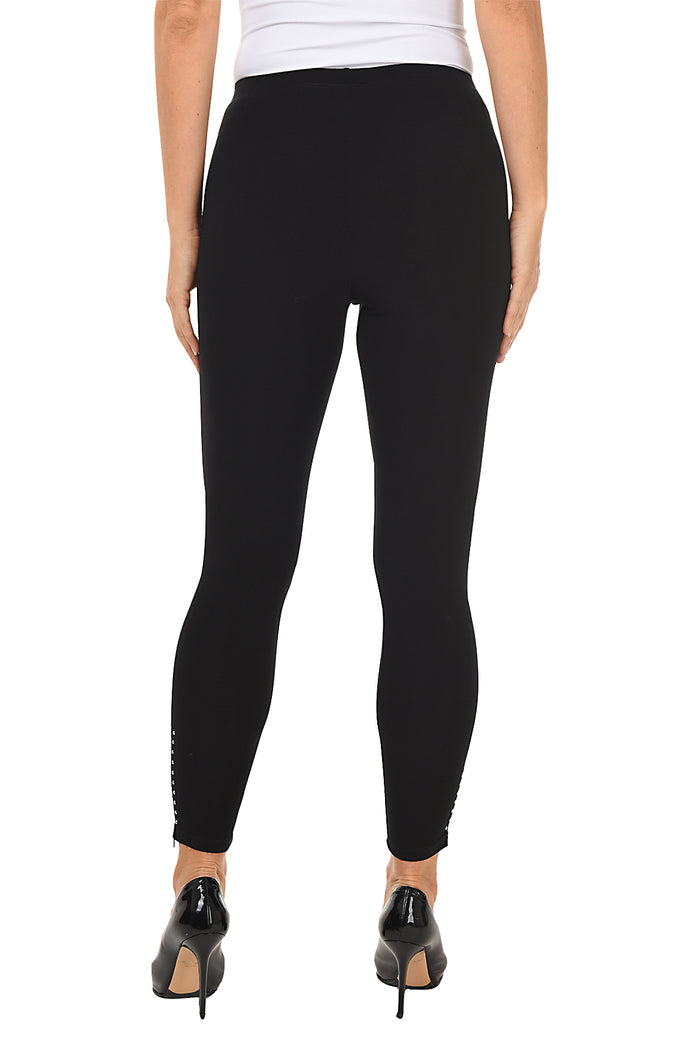 A model wearing black pull-on legging pants with studded embellishment and a zip-up hemline. Back shot.