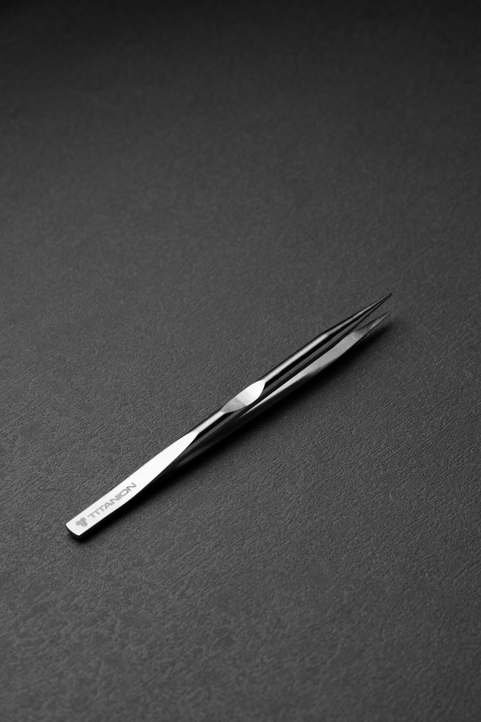 Metallic tweezer on a dark gray background
