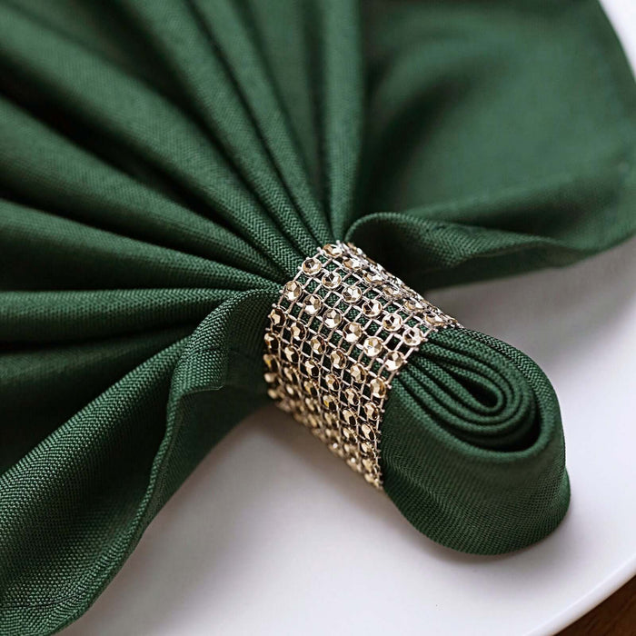 Green napkin elegantly folded with a jeweled ring.