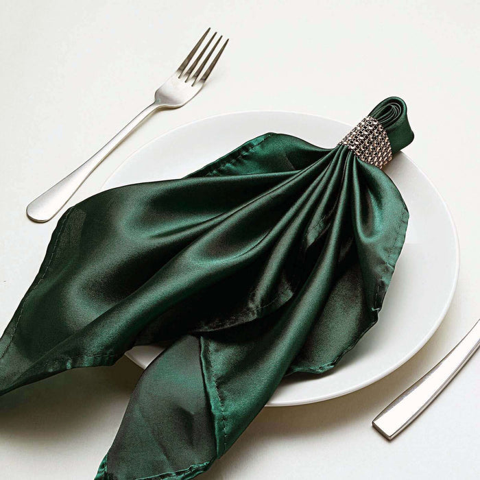 Elegant green satin napkin with jeweled ring on a white plate.