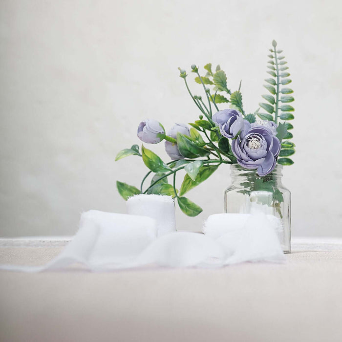 Floral arrangement in a glass jar with white fabric backdrop.