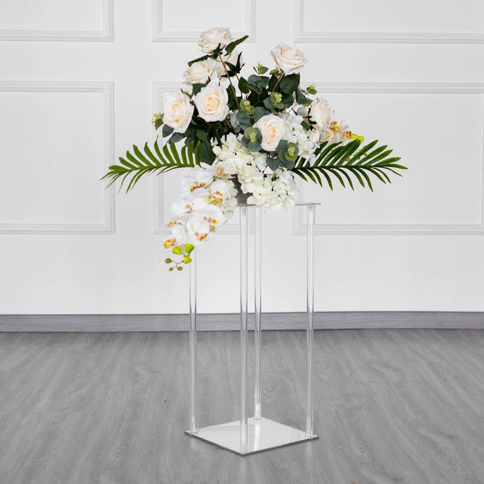 Acrylic flower stand with white roses and greenery on a modern floor.