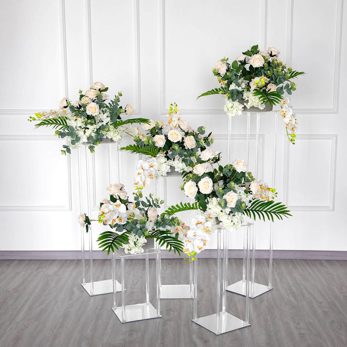 Elegant artificial floral arrangements on clear pedestals in a modern setting.