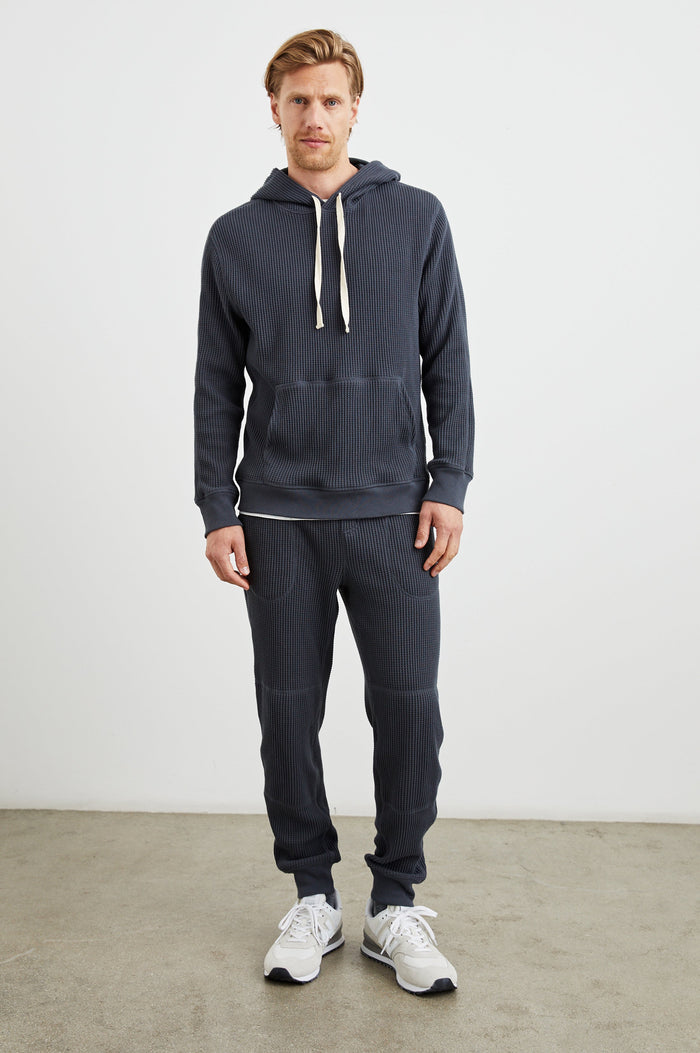 Cooper Waffle Thermal Pants with an Elastic Drawstring Waist, Two Teardrop Front Pockets, Two Back Welt Pockets, Reinforced Knee Patches and Elastic Cuffs in Ink Colorway - Front Full Body View Featured on Model