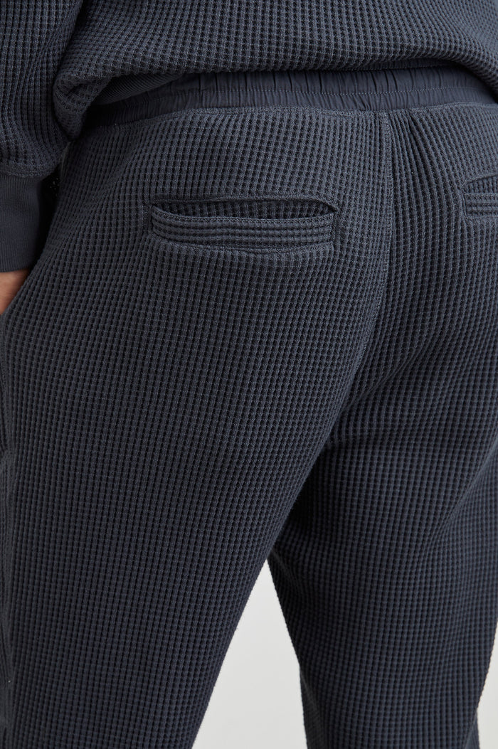 Cooper Waffle Thermal Pants with an Elastic Drawstring Waist, Two Teardrop Front Pockets, Two Back Welt Pockets, Reinforced Knee Patches and Elastic Cuffs in Ink Colorway - Back View Featured on Model
