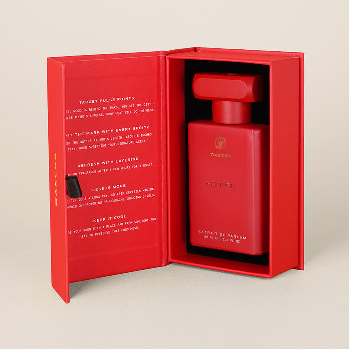 Three-quarter view of Eclipse extrait de parfum in open red gift box showing gold Oakcha logo and black foam lining