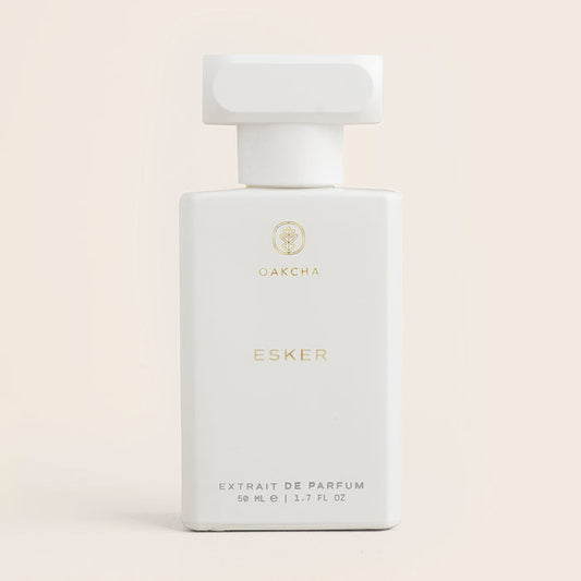 Front view of Esker 50 ml extrait de parfum bottle, matte white bottle with gold Oakcha logo on pale beige background