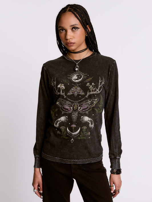 Person wearing a black long-sleeve shirt with intricate designs on a plain background
