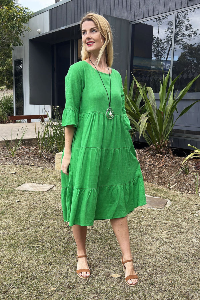 Jade green Hourglass shift tunic dress hanging on a wooden hanger, showcasing its simple, elegant design and smooth fabric.