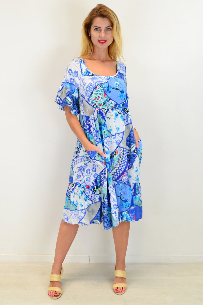 Orientique Kintsugi Tunic Dress with colorful floral patterns and flowing fabric, displayed on a hanger against a neutral background.