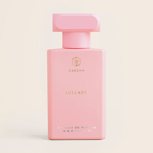 Front view of Lullaby perfume bottle showing a matte pink rectangular bottle with a block cap and small gold logo on a cream background