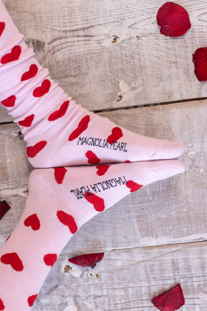 Magnolia Pearl pink artisan socks with red hearts and vintage whimsy on rustic wood floor