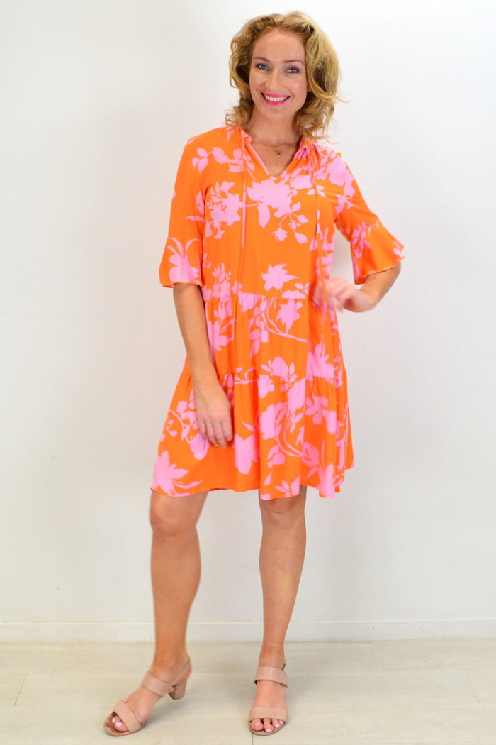 Peony orange maple leaf tiered dress tunic hanging on a mannequin, showcasing the flowy layered design and vibrant fall-inspired colors.
