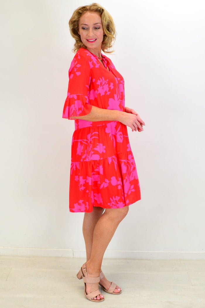 Pink maple leaf tiered dress tunic by Peony, featuring layered fabric and a flowing silhouette, displayed on a hanger.