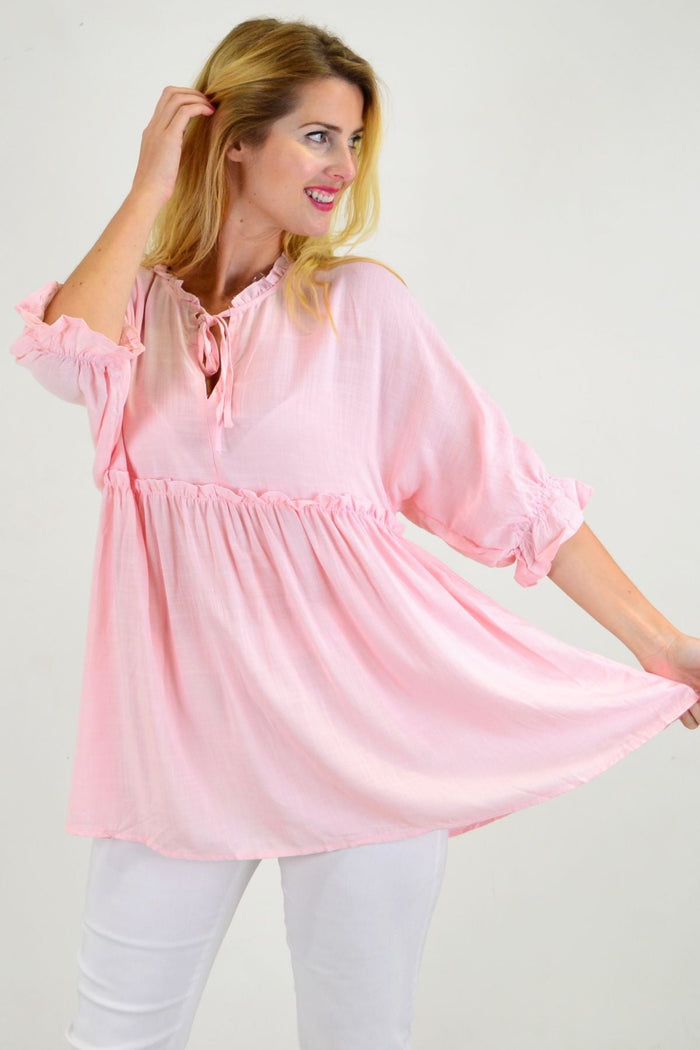 Powder pink Hourglass relaxed fit tunic blouse with long sleeves and a flowing silhouette, displayed on a hanger.