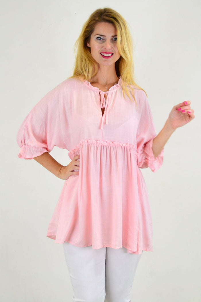 Powder pink relaxed fit tunic blouse by Hourglass, shown hanging on a white background with soft fabric details.