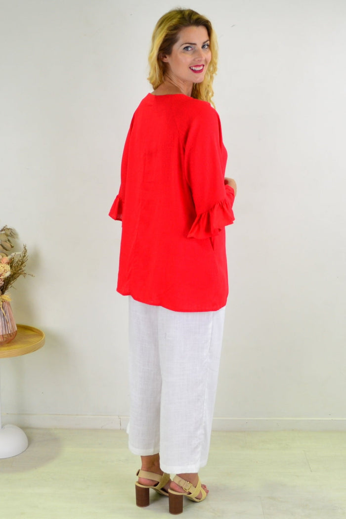 Red Razzle Dazel ruffle sleeve tunic top by Hourglass, featuring flowing fabric and stylish ruffle details on the sleeves.
