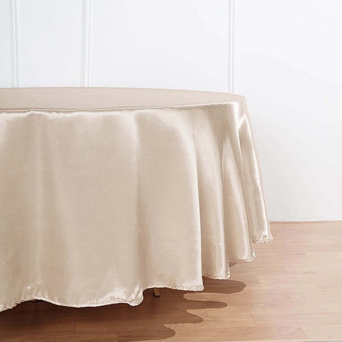 Satin tablecloth in champagne color draping over a round table.