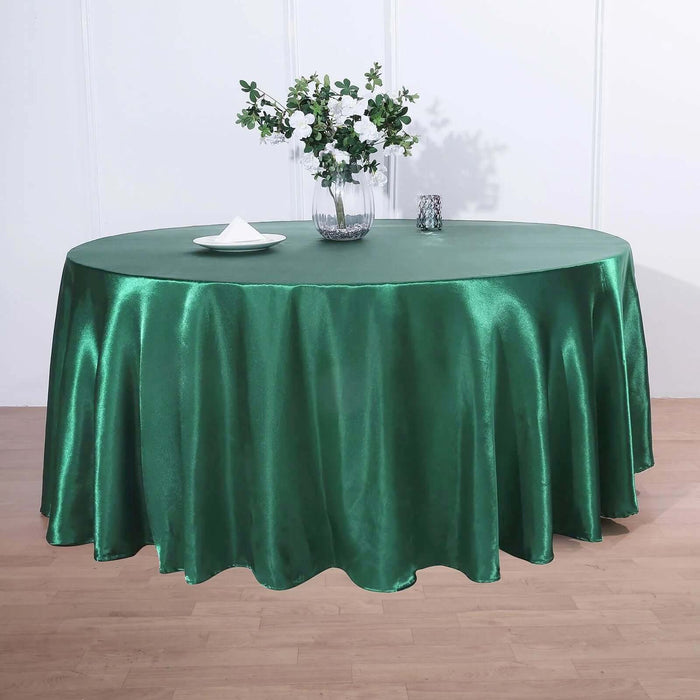 Green satin tablecloth draped on a round table with floral arrangement.