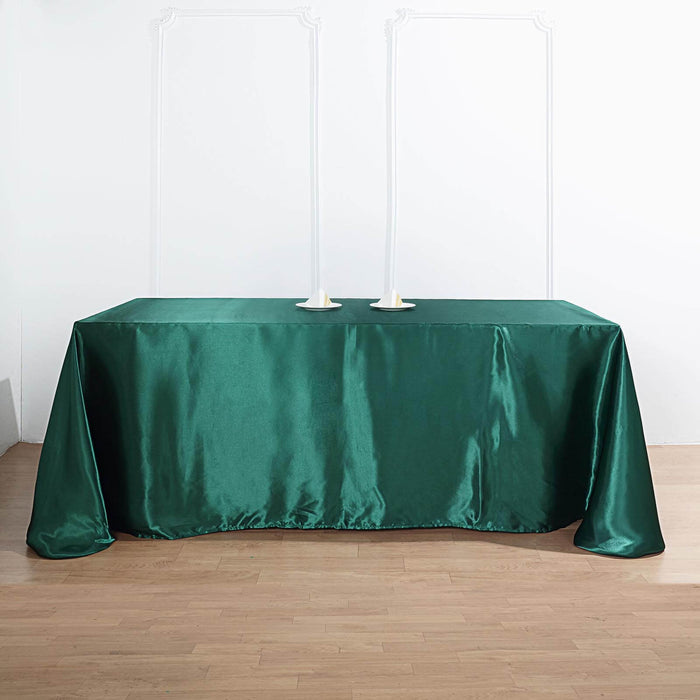 Green satin tablecloth on a wooden floor with candle holders