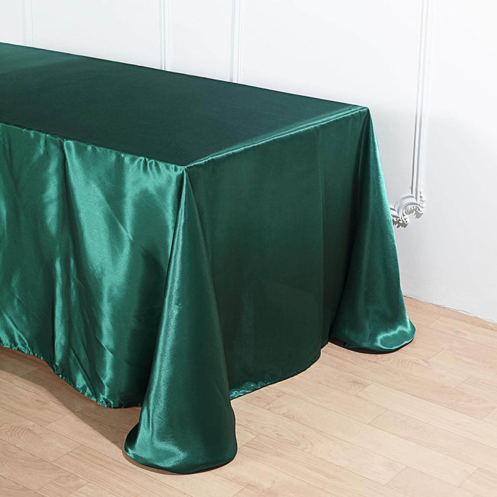 Green satin tablecloth draped over a table in a studio setting.