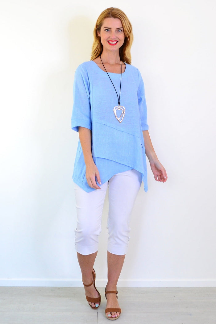 Sky blue layered linen blend tunic top by Ruby Rain, shown on a hanger with soft fabric and relaxed fit details.