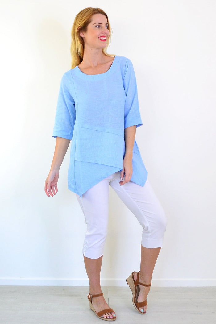 Sky blue layered linen blend tunic top by Ruby Rain, featuring a relaxed fit and flowing design, displayed on a hanger.