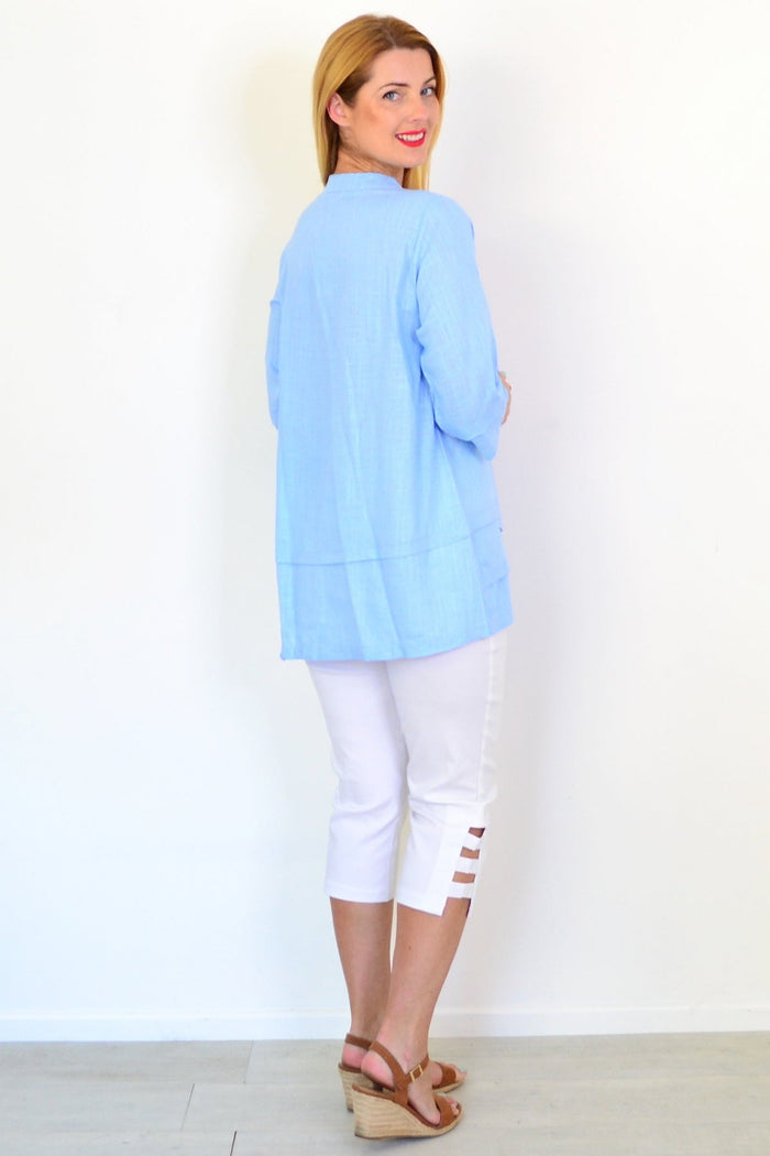 Sky blue linen blend tunic top from Ruby Rain displayed on a hanger, showcasing its relaxed fit and lightweight fabric design.