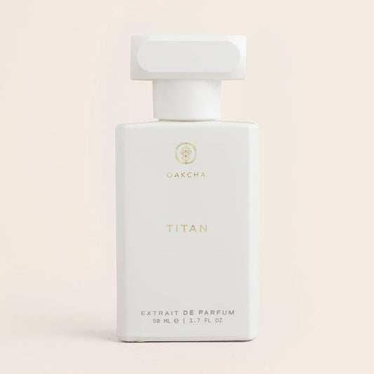 Front view of Titan 50ml extrait de parfum bottle showing white rectangular bottle with gold Oakcha logo and wide cap on pale pink background