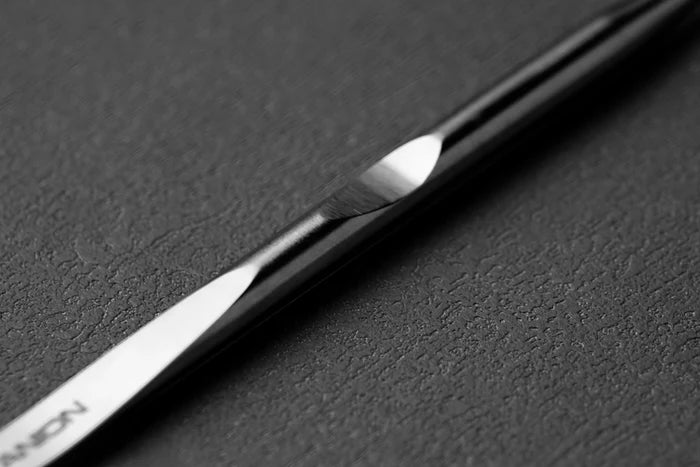 Close-up of a tweezer edge with "Titanion" branding on a dark textured background.