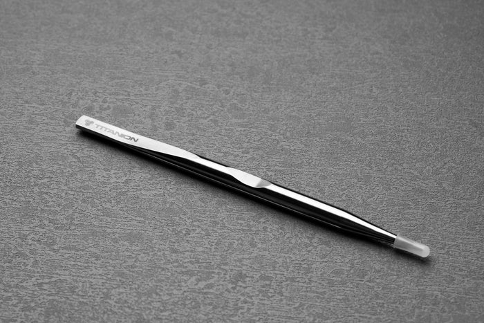 Metallic tweezers on a gray textured surface