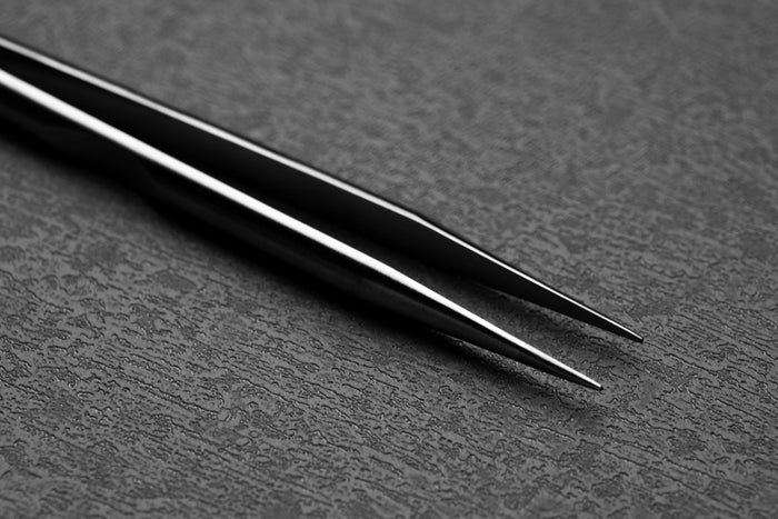 Pair of black tweezers on a textured gray surface