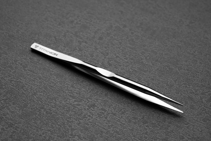 Pair of silver tweezers on a gray textured background