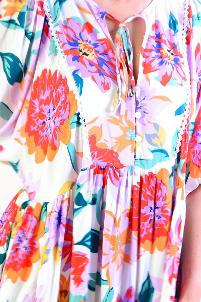 White tropical garden dress tunic from New U Collection, featuring floral patterns and lightweight fabric, displayed on a hanger.