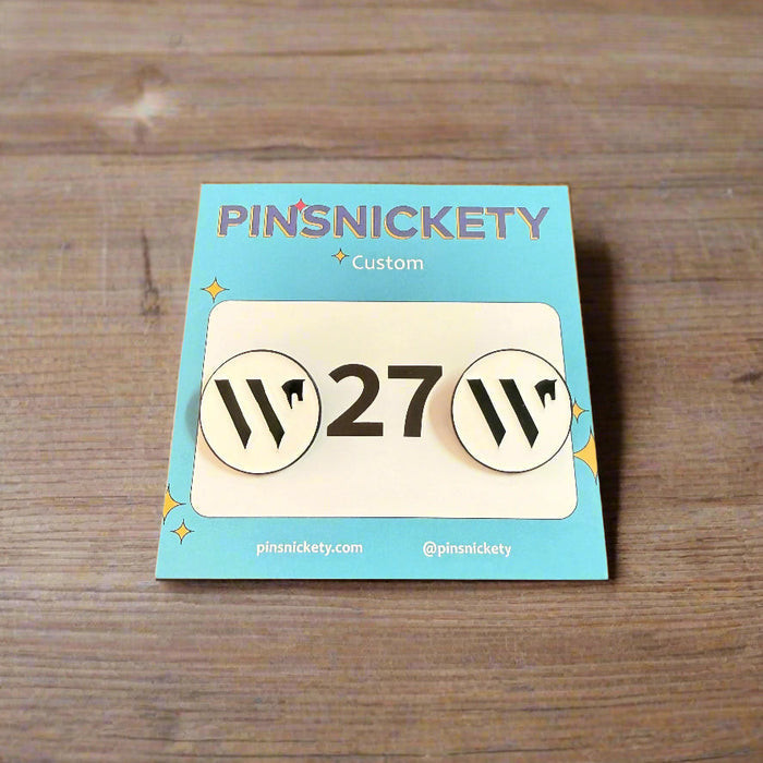 Pins with Wellington International branding on a wooden surface