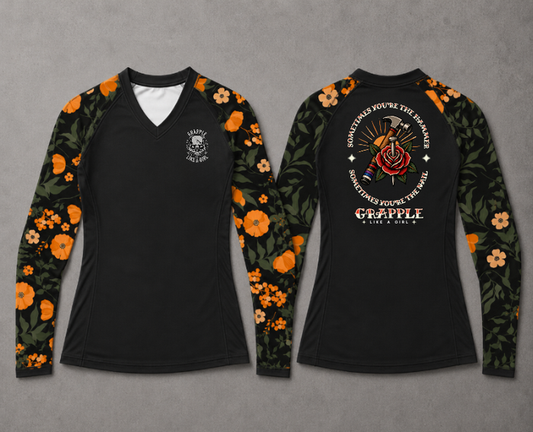 Front and back view of women’s black BJJ rash guard with orange floral sleeves and Grapple Like a Girl graphic